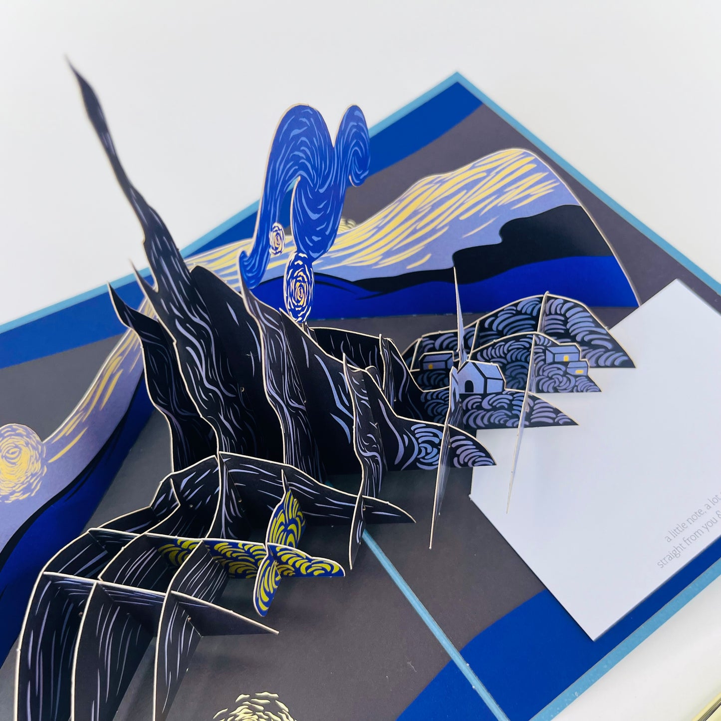 Pop-up card with a blue and black design featuring a landscape and abstract elements.