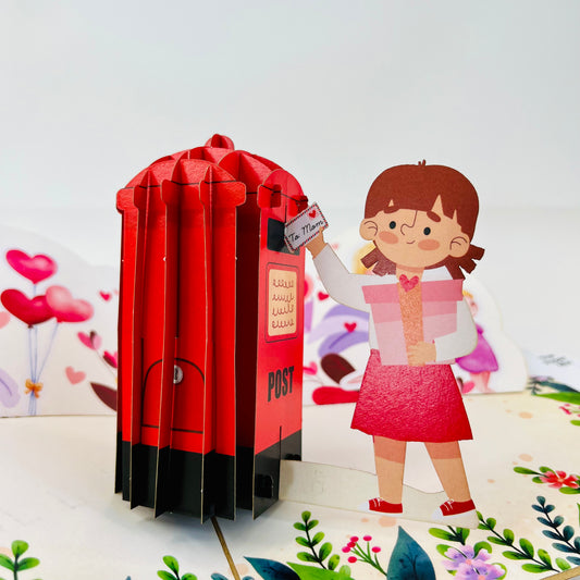 A 3D greeting card featuring a red mailbox and a cartoon-style girl character in front of a floral background.