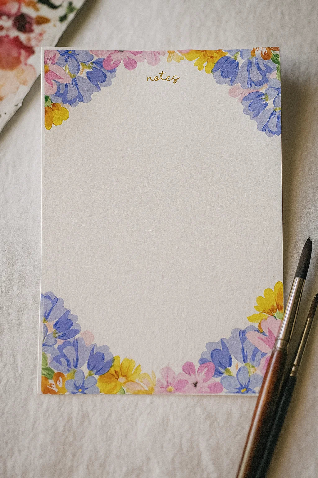 Floral notepad with a pen on a textured surface