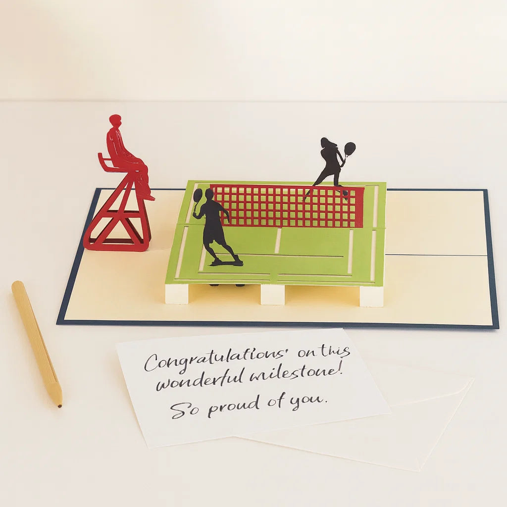 Pop-up card with badminton players and net on a court, with a pen and message underneath.