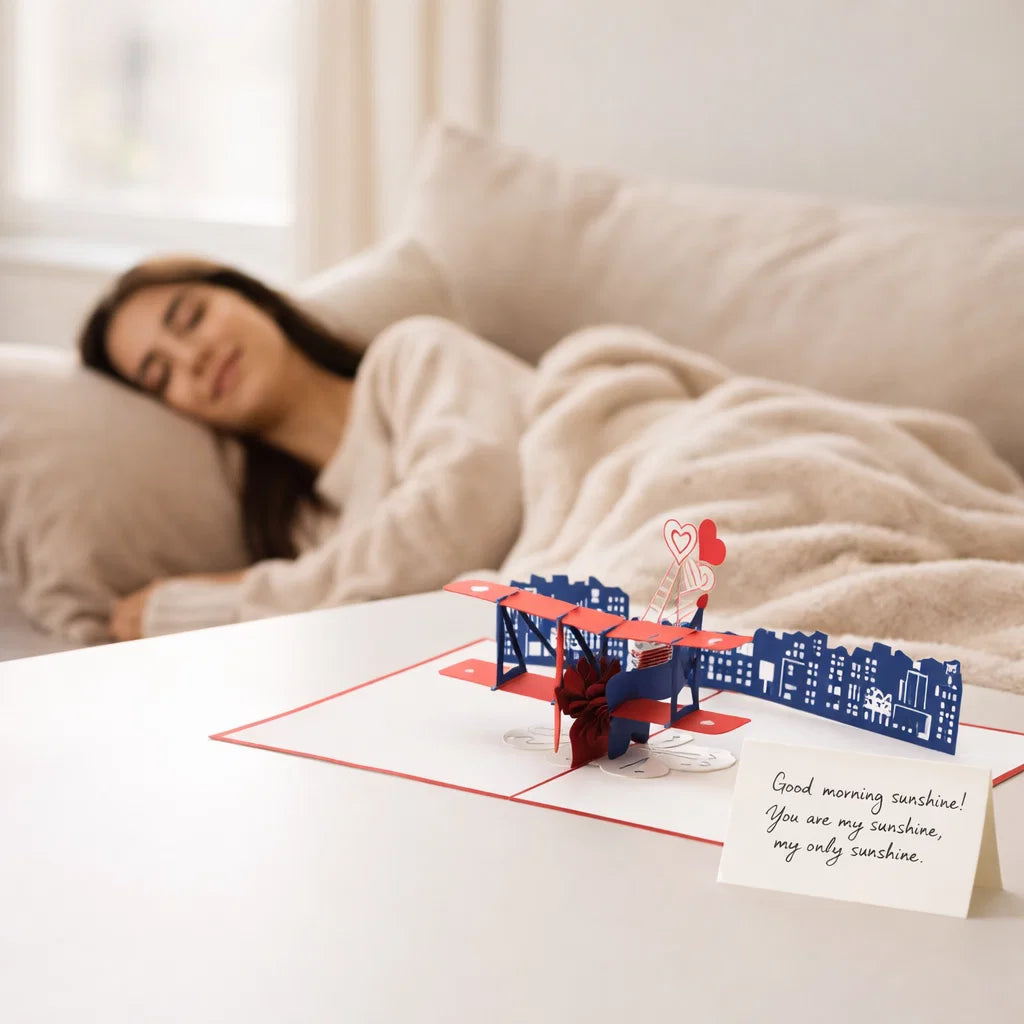 Woman lying in bed with a 3D pop-up card on a table