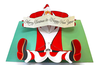 Pop-up card with Santa Claus holding a 'Merry Christmas & Happy New Year' sign on a white background.